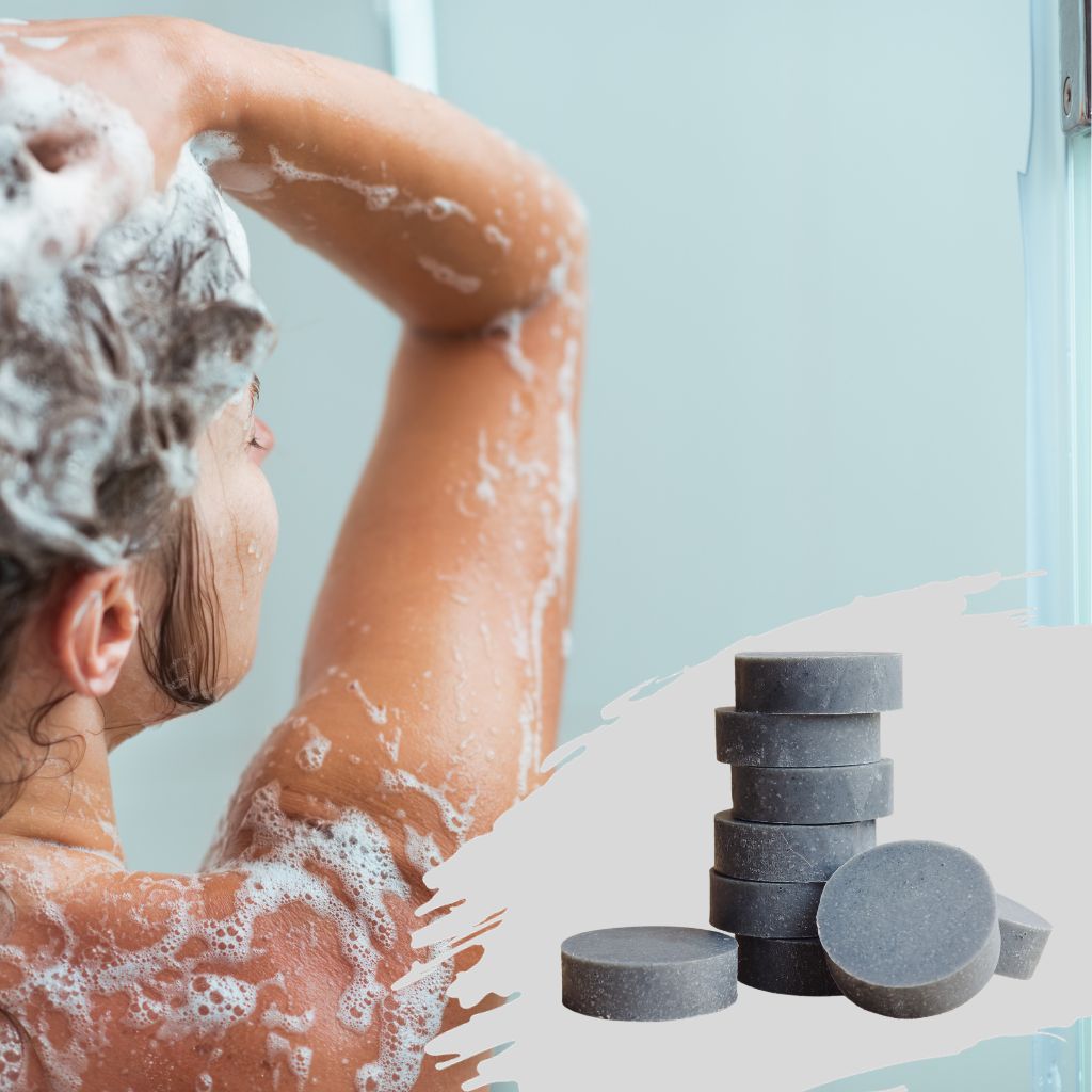 BotaniVie. Natural Shampoo. Model in the shower applying natural shampoo to her hair. A stack of grey coloured natural shampoo's in the corner.