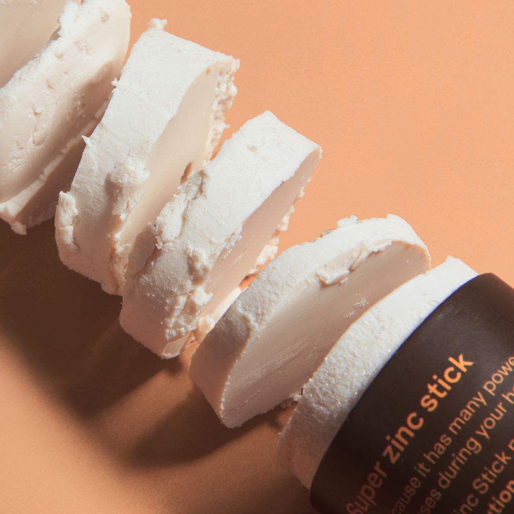 Sol de Ibiza Face & Body Plastic Free Zinc Stick SPF30 Sun screen. Cardboard tube. Natural, recyclable, vegan, cruelty free sun protection for all skin types, and adults and children. flatlay with product texture up close.