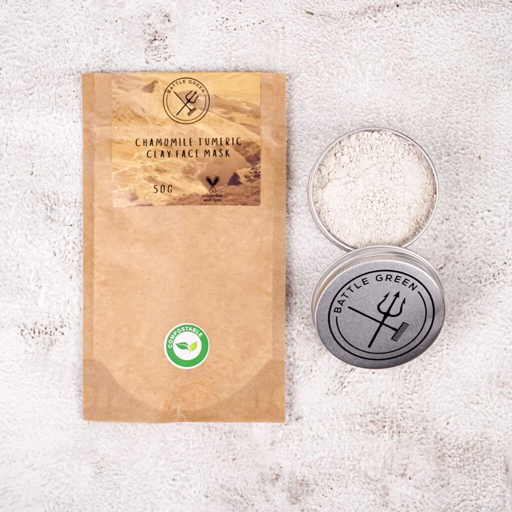Battle Green Chamomile Turmeric Clay Face Mask. flatlay on table with travel tin. Powder in dry format. vegan and plastic free.
