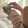 UpCircle - Body Cream jar being held by a model using her fingers to scoop the product out.