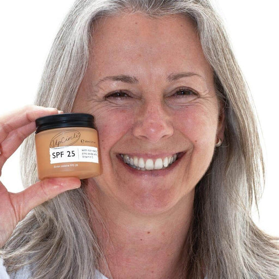 UpCircle - SPF 25 Mineral Sunscreen. lifestyle image of user smiling and holding the product.