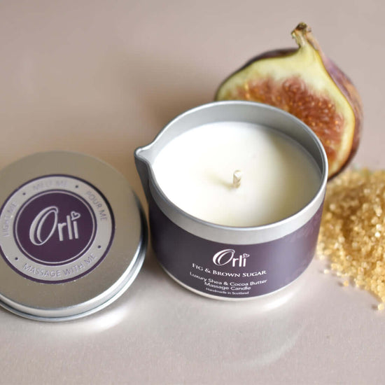 Orli Fig and Brown Sugar Massage Candle in Aluminium tin with lid off. ready to use. Fig in background.