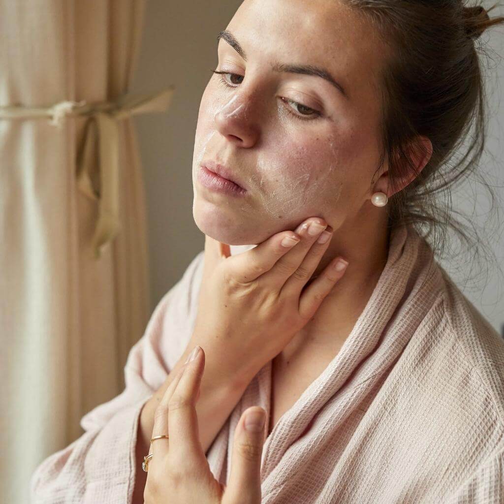 Upcircle Face Moisturiser being applied to a models face. She is rubbing it into her face.