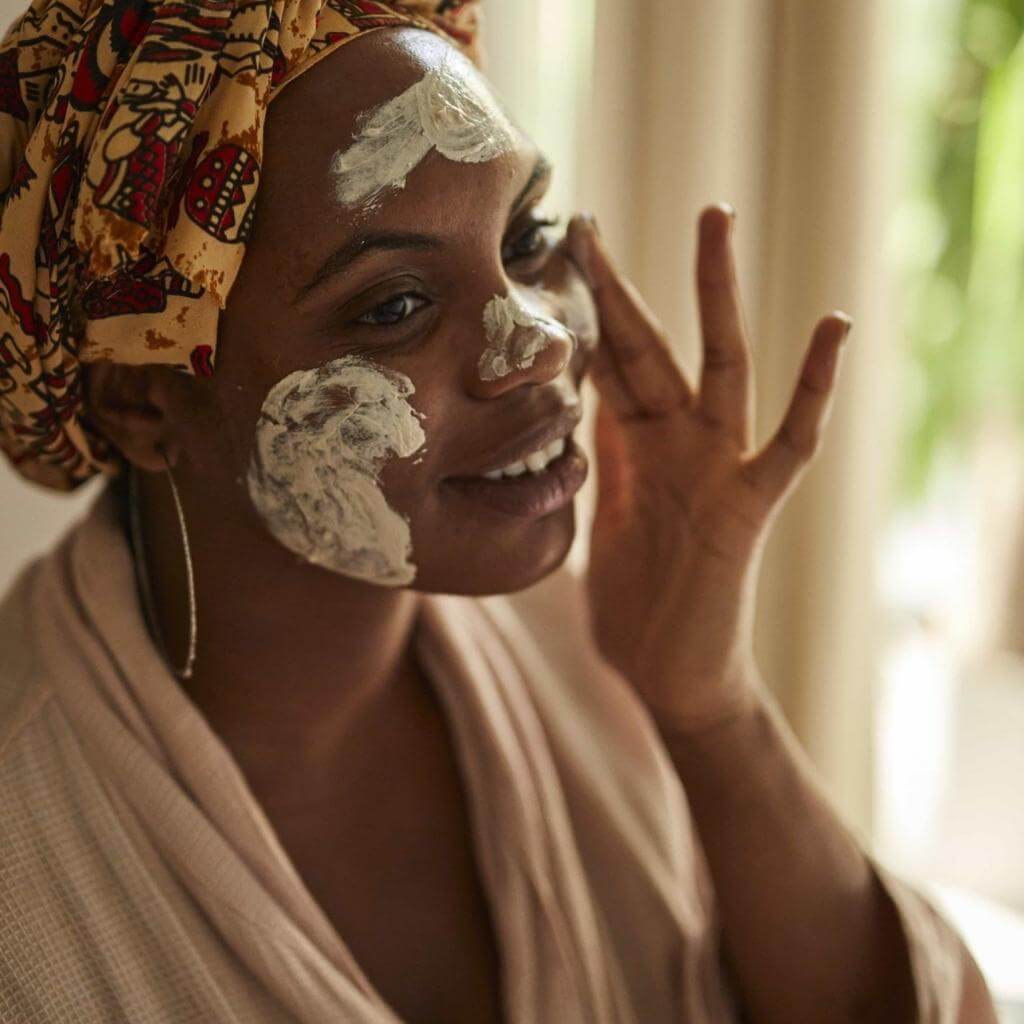 UpCircle - Kaolin Face Mask being applied to the face of a model. The product is being generously applied and white in colour.