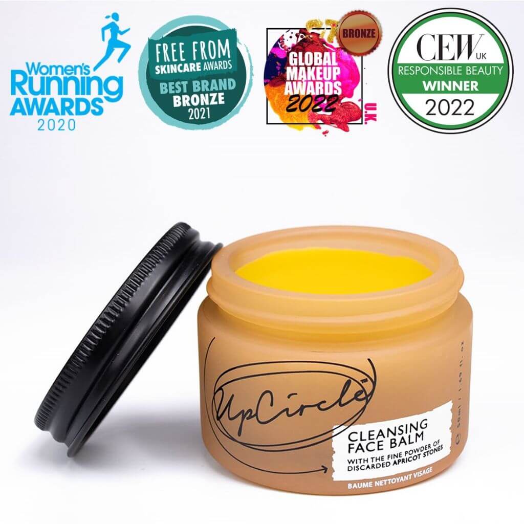 Upcircle Cleansing Face Balm with lid off and yellow balm visible inside with a white background. Awards: Women's Running Awards 2020, Free From Skincare Awards Best Brand Bronze 2021.