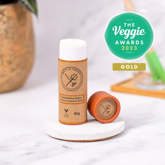 Battle Green Mandarin and Neroli Deodorant Stick with Award from The Veggie Awards 2023 Gold Winner. With lid off with a table background.