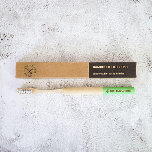 Battle Green Bamboo Toothbrush with Castor Oil Bio Bristles. biodegradable cardboard box. on sink. all natural.