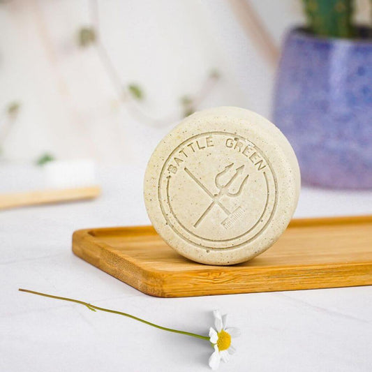 Battle Green Chamomile Vegan Natural Deodorant Bar. on display with chamomile sprig. fragrance free and for sensitive skin. on wooden board.