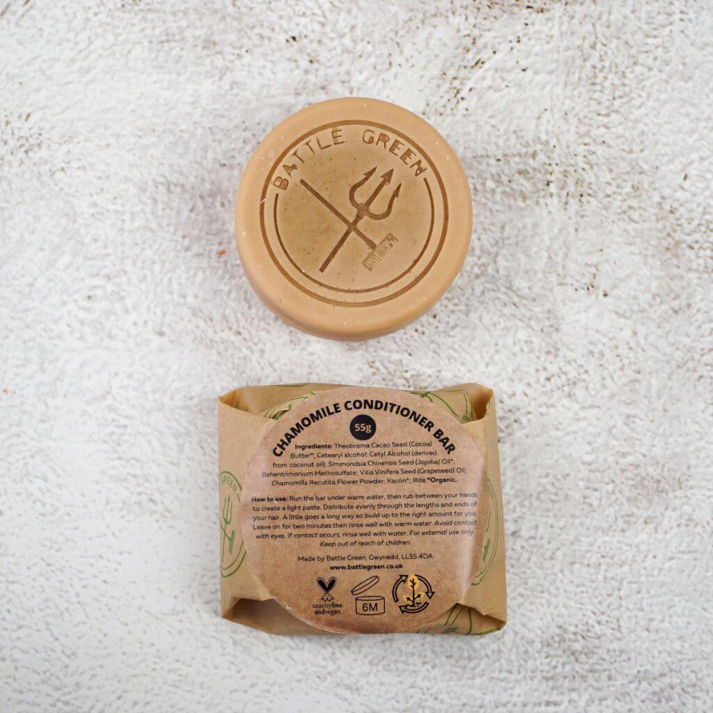 Battle Green Fragrance Free Chamomile Conditioner Bar. with bar on display with a fully wrapped bar. the packaging is compostable and printed with plant based ink. handmade in small batches, palm oil free, PETA certified Cruelty-Free & Vegan.