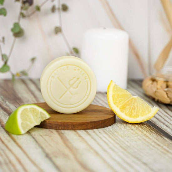 Battle Green Citrus Solid Hair Conditioner Bar. uplifting and eco-friendly. On display with lemon and lime slices and on a wooden board. with Plastic Free Packaging.
