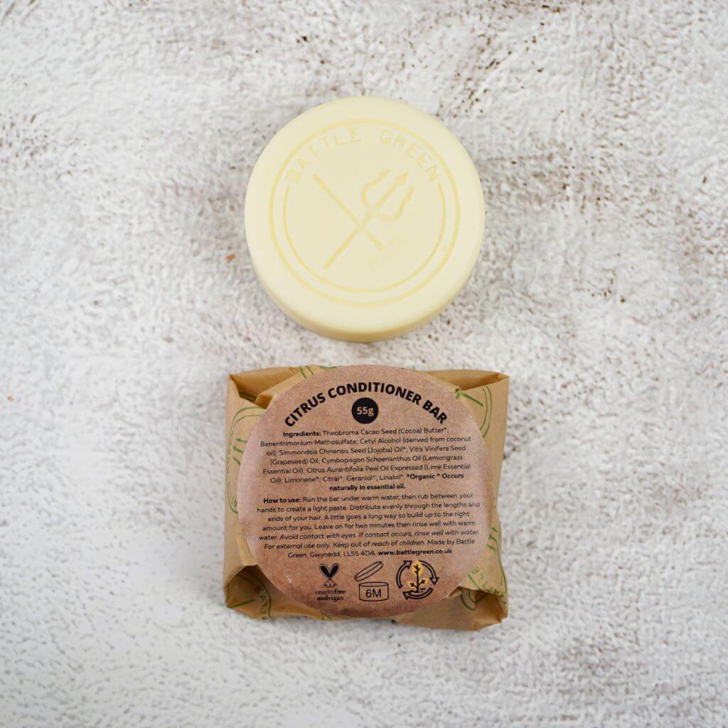 Battle Green Citrus Solid Hair Conditioner Bar. with bar on display with a fully wrapped bar. the packaging is compostable and printed with plant based ink. handmade in small batches, palm oil free, PETA certified Cruelty-Free & Vegan.