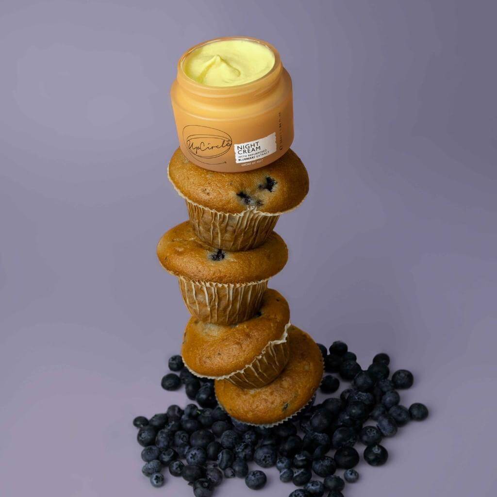 UpCircle - Night Cream jar with lid off and cream visible being displayed on blueberries and blueberry muffins.