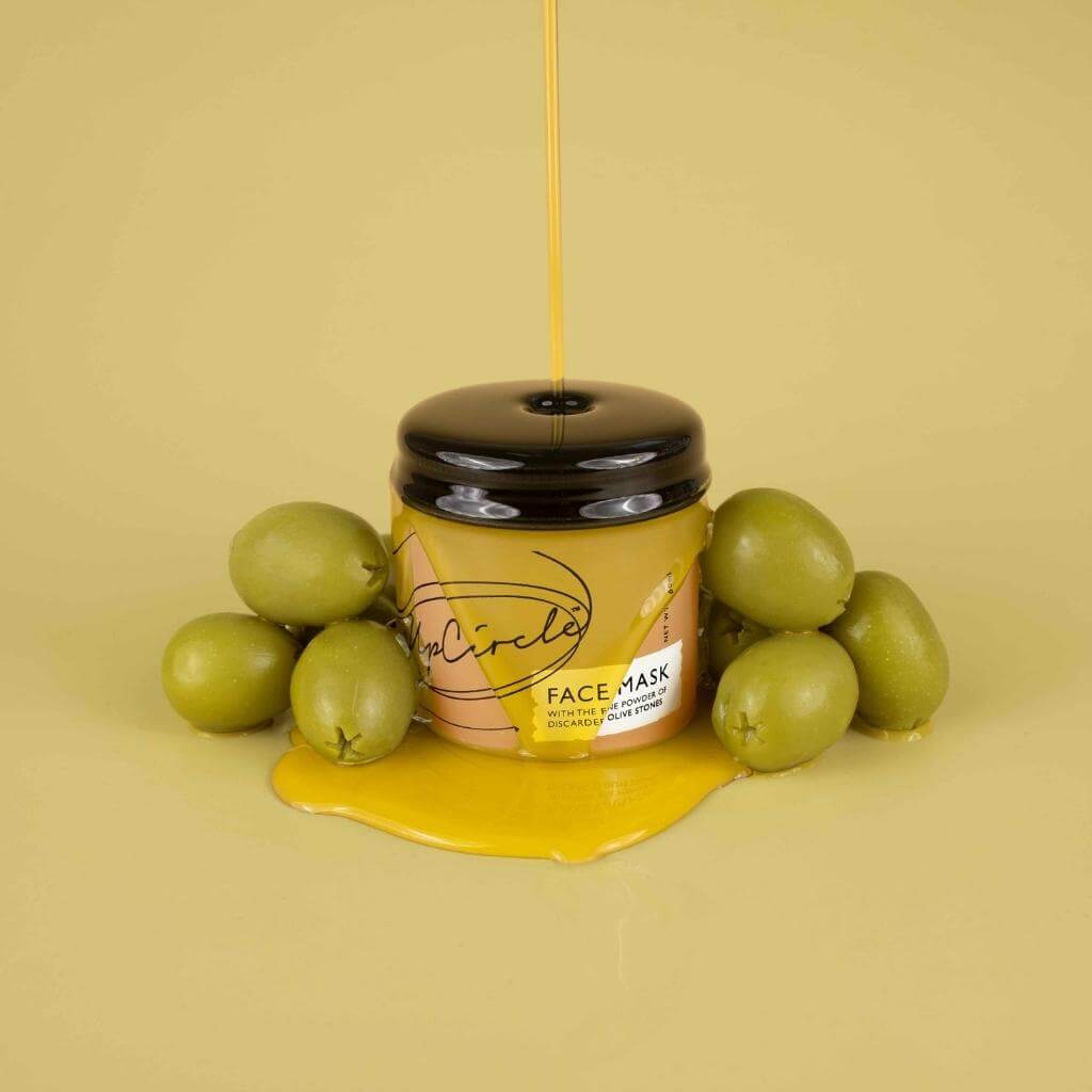 UpCircle - Kaolin Face Mask with fresh olives beside jar and all being drizzled with olive oil.