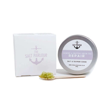 The Salt Parlour Jasmine & Matcha Green Tea REPAIR salt and sulphur scrub with wooden spoon holding a small amount of salt scrub. The box and tin are upright on a white background