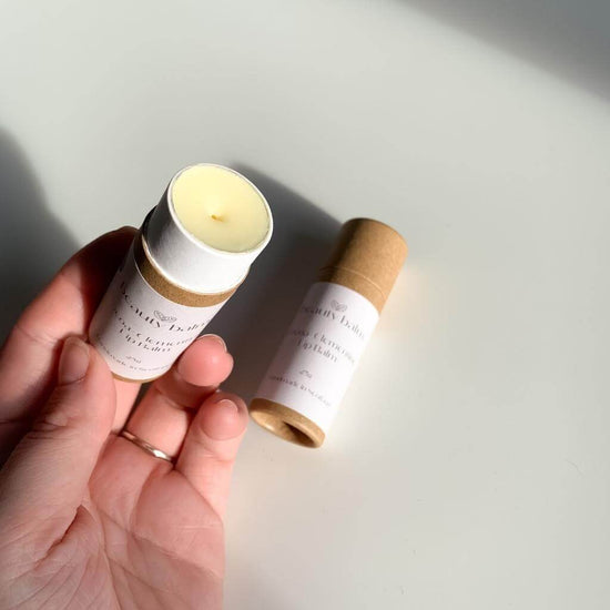 Beauty Balm Cocoa and Clementine Lip Balm in Cardboard Tubes being held with lid off and white balm visible.