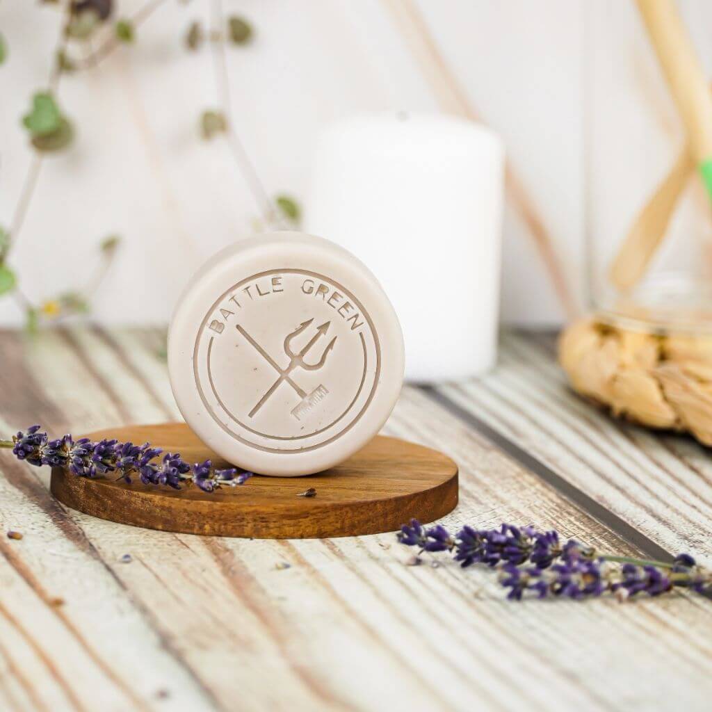 Battle Green Lavender Solid Hair Conditioner Bar. uplifting and eco-friendly. On display on a wooden board. with Plastic Free Packaging.