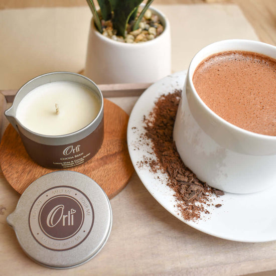 Orli Cocoa Bean Massage Candle in Aluminium tin. Hot chocolate, on a lifestyle image. Lid off.