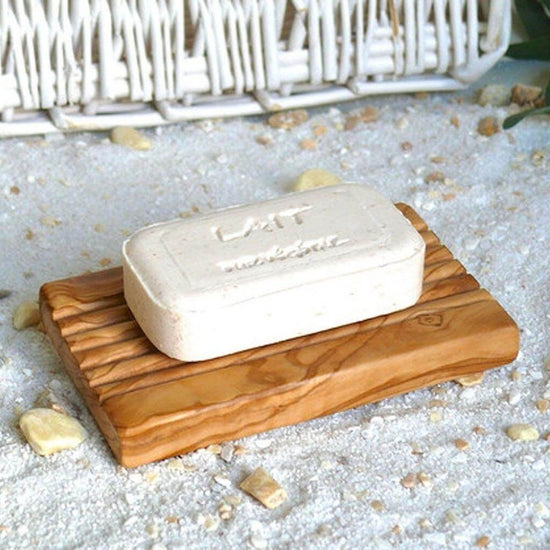 Olive wood grooved soap dish with a soap bar on top. naturally non-porous wood, exceptionally hard and strong.