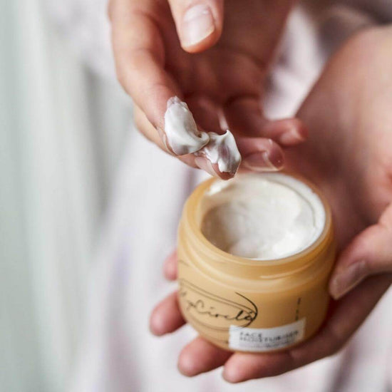 Upcircle Face Moisturiser with the jar open and a models fingers showing the product.