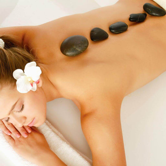 Orli Calm Therapy Massage Candle. Model on massage lounge with stones on her back.