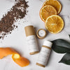 Beauty Balm Cocoa and Clementine Lip Balm in Cardboard Tubes Lifestyle photo. With Clementine and Chocolate on a tile.