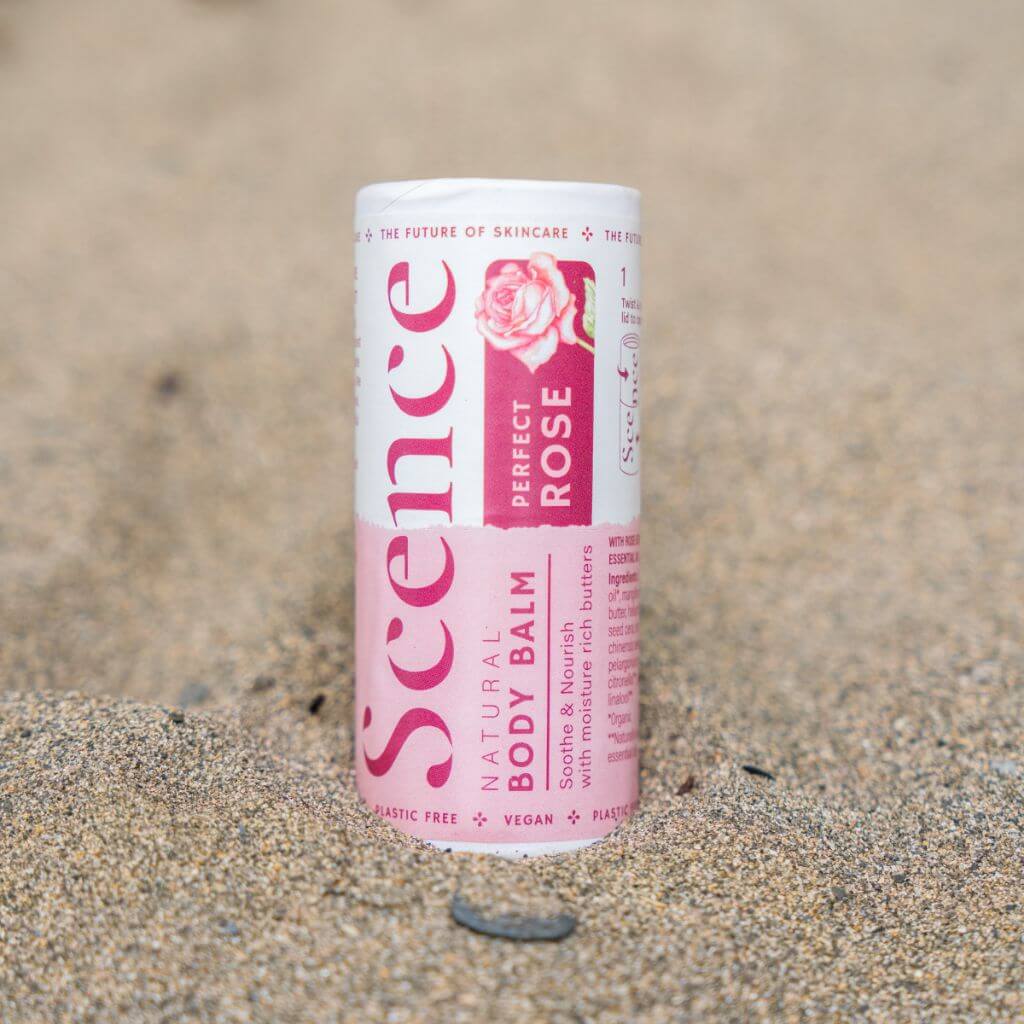 Scence Perfect Rose Natural Solid Body Balm. Lifestyle image. Product on the beach. Vegan certified, cruelty free, plastic free, compostable packaging.