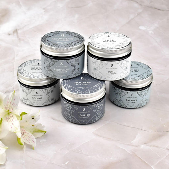 Silvan Skincare. Face Cream. Group image with all the range, and a flower. products stacked. for all skin types and conditions. made in the uk. plastic free and cruelty free.