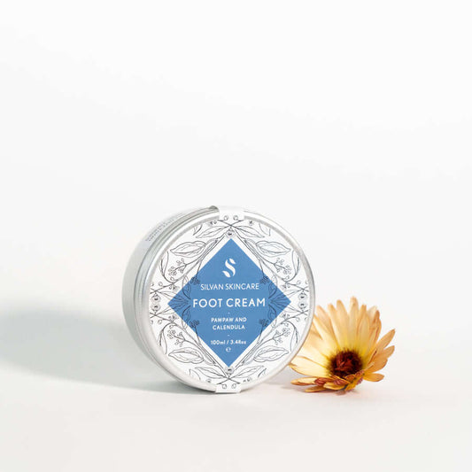 Silvan Skincare. Foot Cream. Foot Cream with Pawpaw and Calendula. 100ml. Aluminium tin and lid. On a white background. with flower.