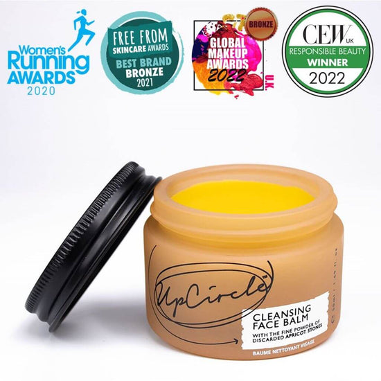 Upcircle Cleansing Face Balm with lid off and yellow balm visible inside with a white background. Awards: Women's Running Awards 2020, Free From Skincare Awards Best Brand Bronze 2021.